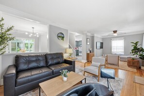 Un salon moderne avec un canapé en cuir, une table basse en bois et un coin repas comprenant une petite table et des chaises.
