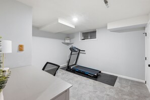 Une salle de sport à domicile équipée d’un tapis de course, d’un bureau et d’une chaise.