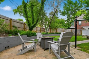 Une terrasse extérieure avec des fauteuils Adirondack et un foyer.