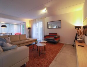 A modern living room with a sofa, armchair, coffee table, and floor lamp. - Beach Villa With Sauna in Makkum (Makkum)