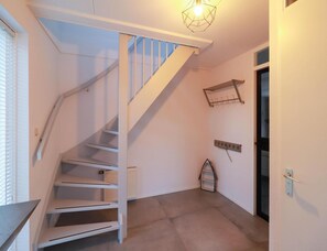 A staircase with white railings and a light fixture above it. There is a radiator on the wall and a door with a handle. - Beach Villa With Sauna in Makkum (Makkum)