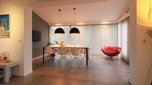 A modern dining area with a table and chairs, a red chair, and a painting on the wall. - Beach Villa With Sauna in Makkum (Makkum)