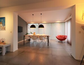 Ein stilvoller Essbereich mit Tisch und Stühlen, ein roter Sessel und ein Bild an der Wand.