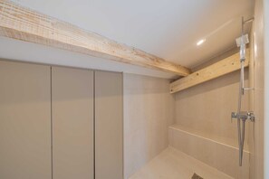 Ein modernes Badezimmer mit Dusche, Holzbalken und Fliesenboden.