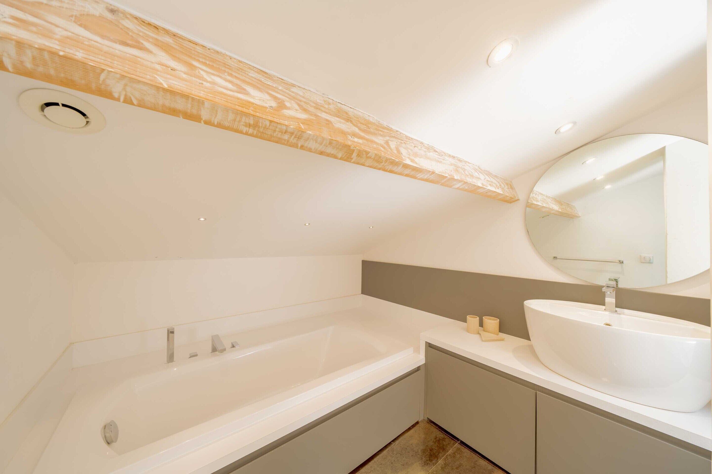 Een moderne badkamer met een vrijstaand bad, een rond wastafel en een grote spiegel.