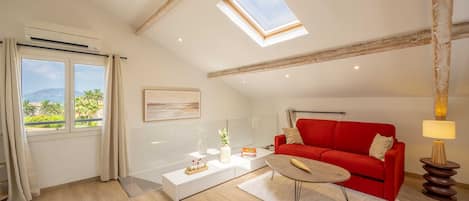 A modern living room with a red sofa, a coffee table, and a skylight.
