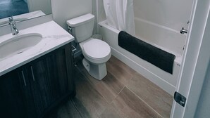 Un baño moderno con lavamanos, inodoro y bañera blancos.