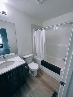 A modern bathroom with a white sink, toilet, and bathtub. - Fully equipped townhouse with a garage, 14 minutes from YYC Airport. Wi-Fi. (Airdrie)