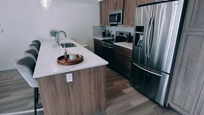 Una cocina moderna con una isla central, electrodomésticos de acero inoxidable y armarios de madera.