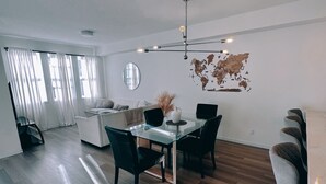 Un espacio de estar moderno con comedor, cocina y un ventanal con cortinas.
