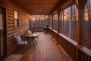 Eine Holzhütte mit verdeckter Veranda, einem Esstisch und Stühlen.
