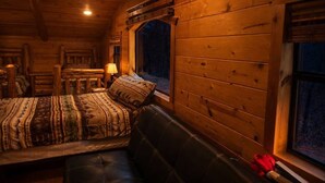 A cozy log cabin room with a bed, a bench, and a window. - Arrowhead Ridge 3 bedroom 3 bathroom, hot tub, wrap around deck. (Broken Bow)