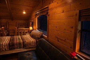 Ein gemütliches Blockhaus-Zimmer mit Bett, Bank und Fenster.
