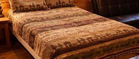 A wooden cabin bedroom with a bed, a window, and a nightstand.