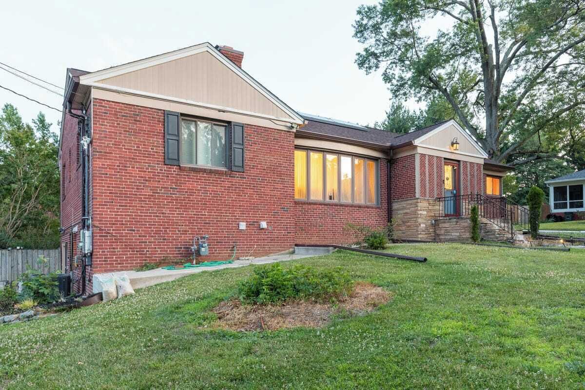 A two-story brick house with a front porch and a small front yard.