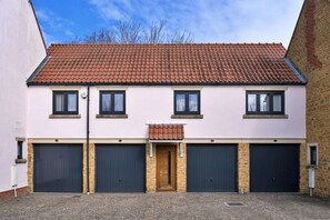 A two-story building with a red-tiled roof, four windows, and four garage doors. - Somerset Countryside Stay (Martock)