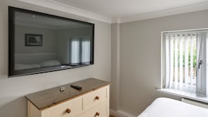 Un dormitorio con un espejo grande, un aparador de madera, una cama y una ventana con persianas.