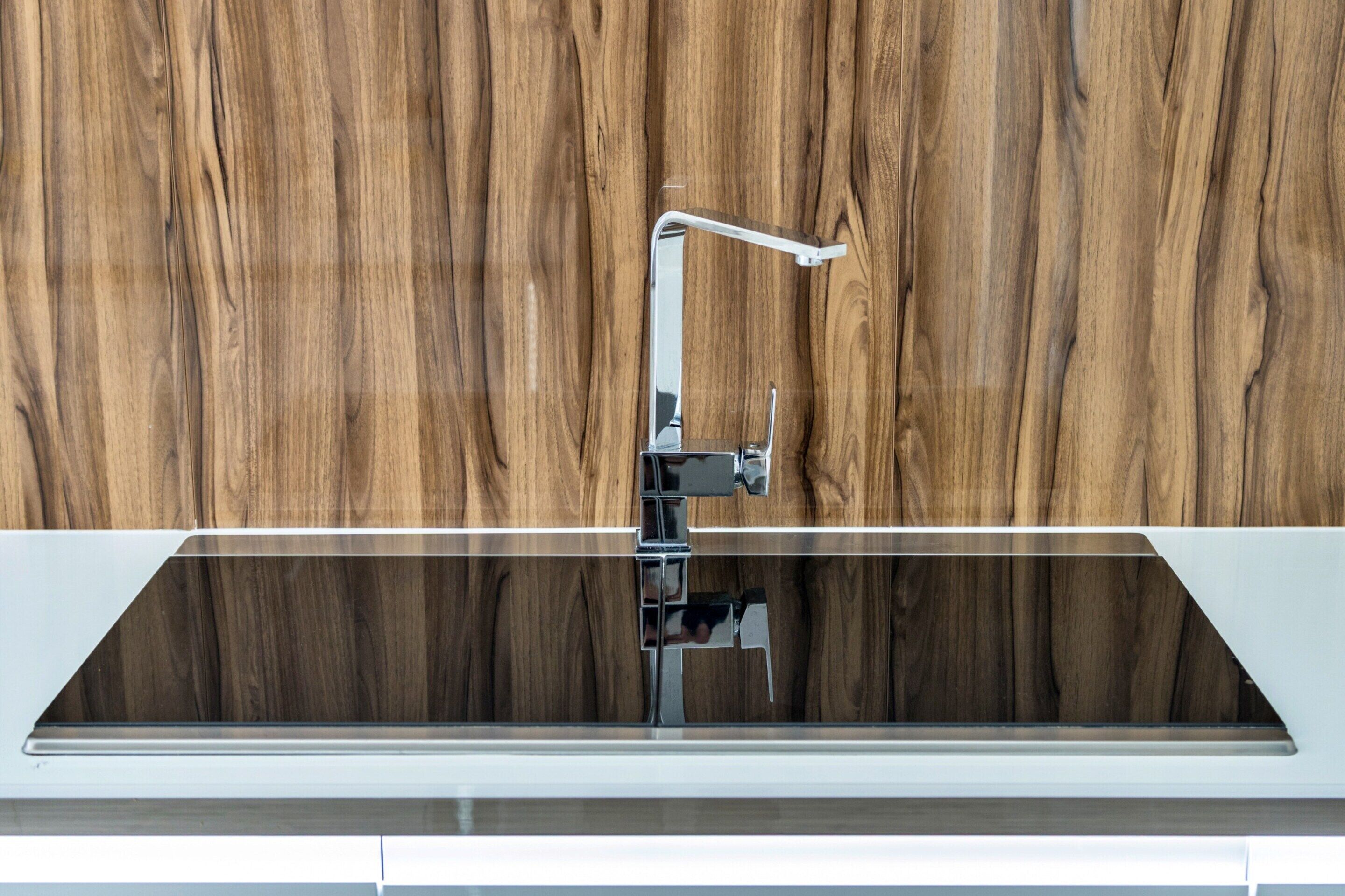 A modern kitchen with a sleek, white countertop and a stainless steel faucet.