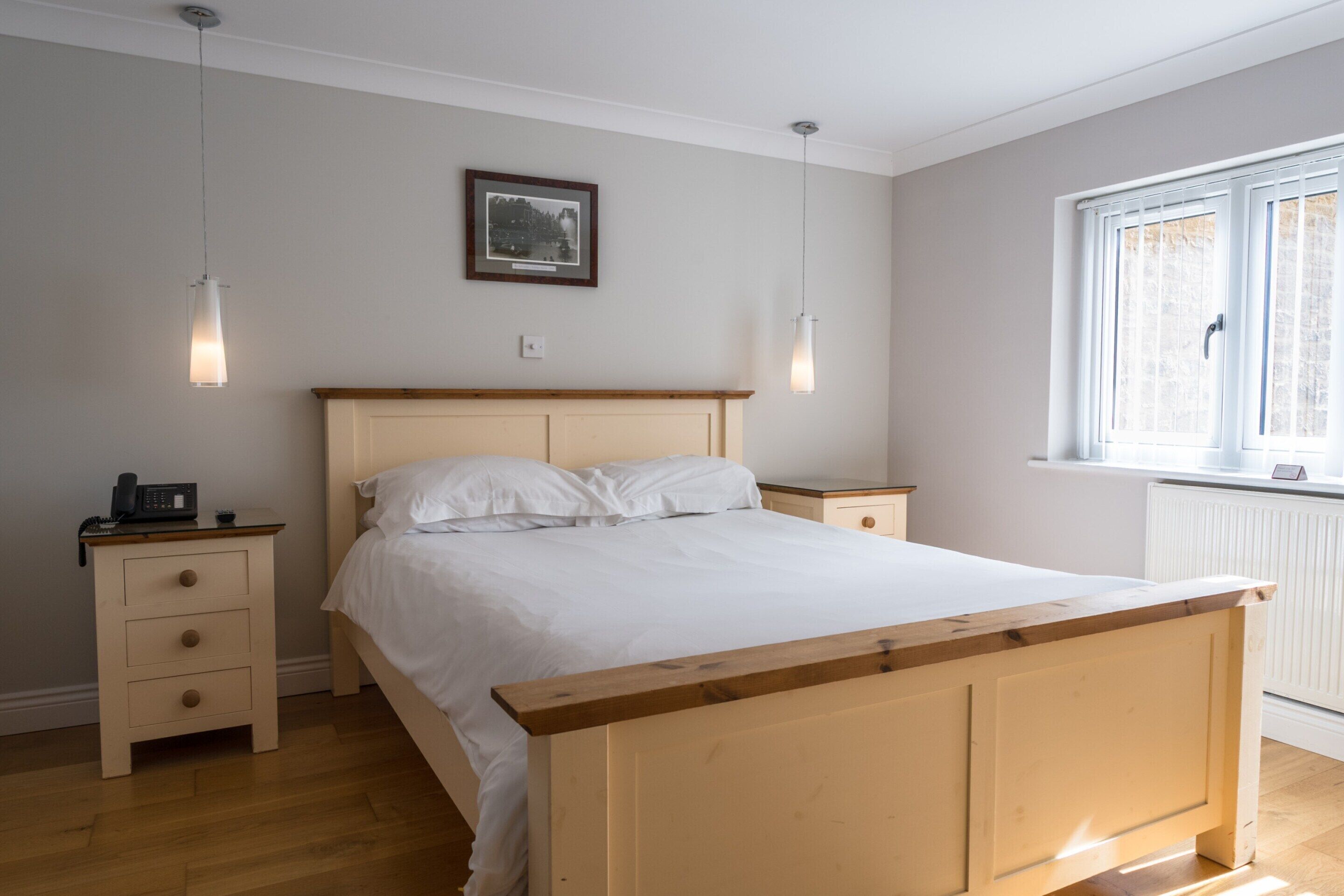 Un dormitorio con cama de madera, mesitas de noche y un ventanal con persianas.