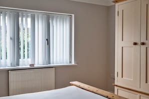 Un dormitorio con ventana, radiador y armario.