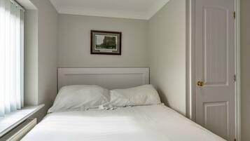 A bedroom with a bed, a framed picture on the wall, and a door.