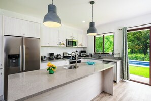 A modern kitchen with stainless steel appliances, a central island, and pendant lighting.