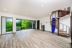 Une pièce spacieuse avec un plancher en bois, de grandes portes-fenêtres coulissantes donnant sur un balcon et un escalier en colimaçon.