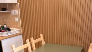 A dining table with four chairs, a kitchen area with cabinets and a countertop, and a tiled floor. - AmdarVillage Cozy Garden Apt. (Eilat)