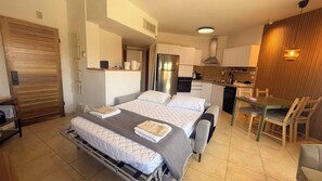 A compact hotel room with a bed, bedside tables, a small kitchenette, and a dining area. - AmdarVillage Cozy Garden Apt. (Eilat)