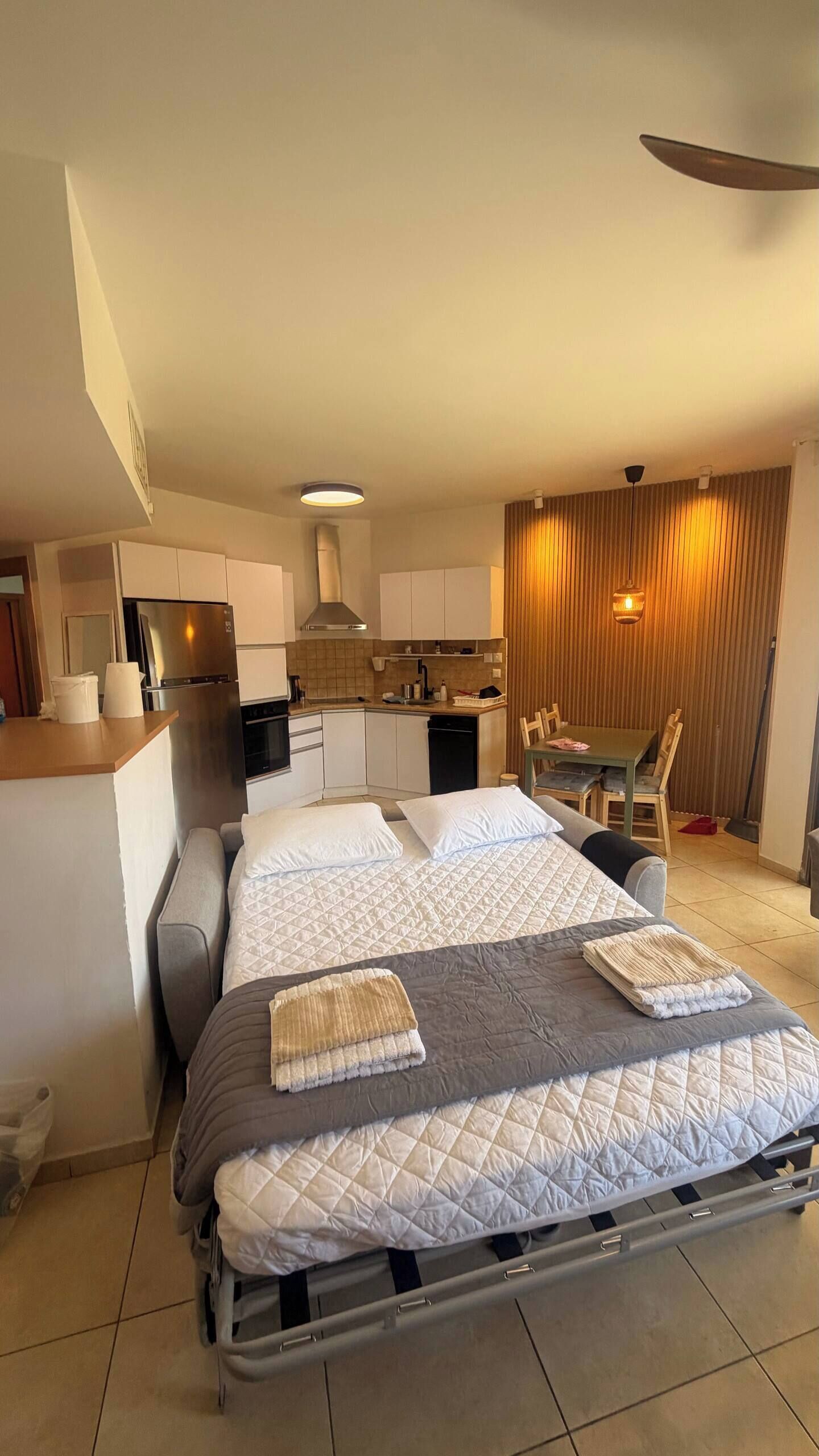 Ein kleines Hotelzimmer mit Bett, Küchenzeile und Essecke.