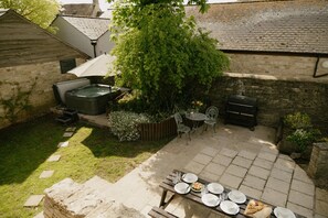 A patio with a hot tub, outdoor seating, and a barbecue grill. - Heritage Holiday Barn With Garden (Lechlade)