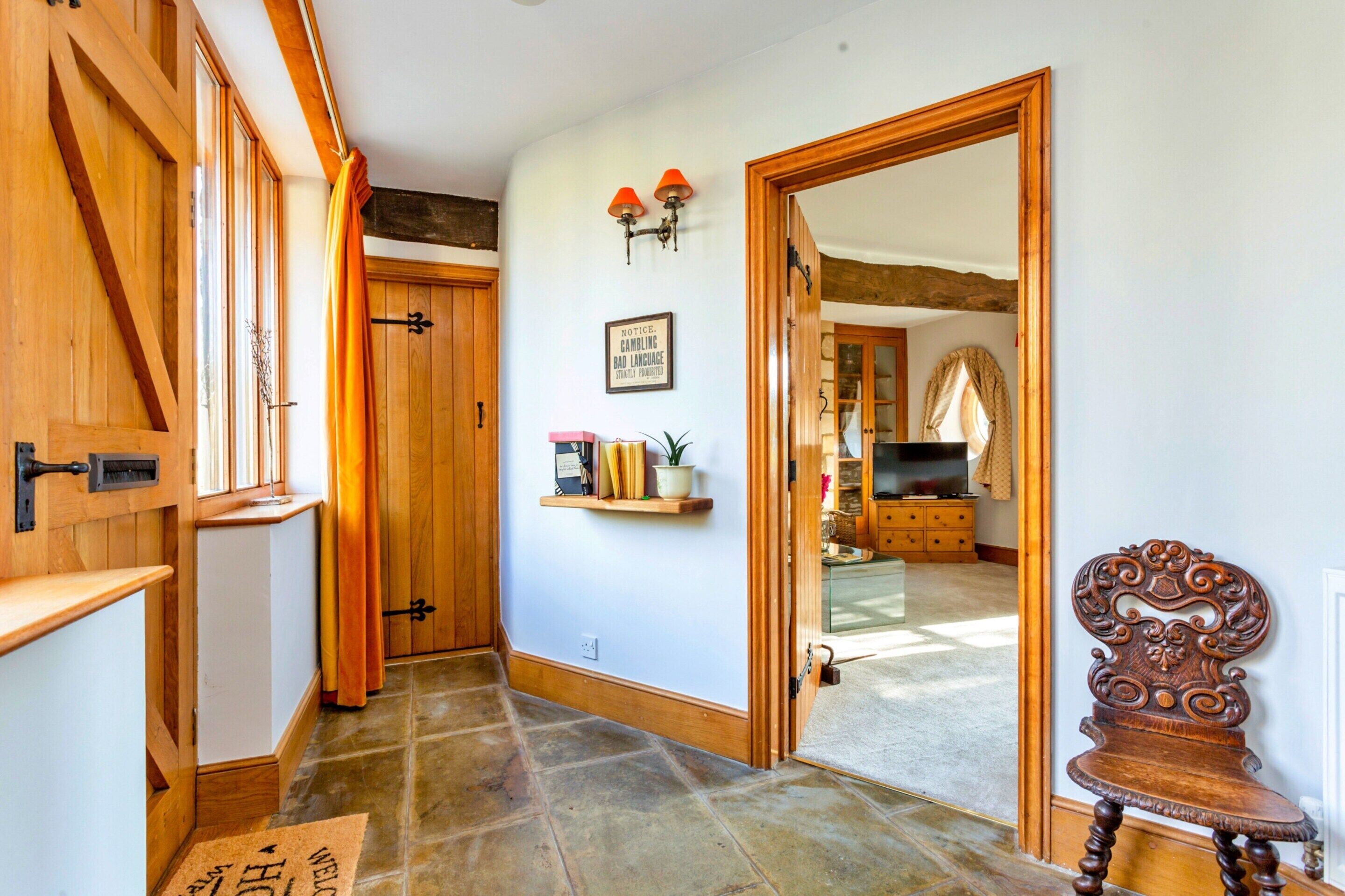 A hallway with wooden doors, a shelf with books, a mirror, and a wooden chair.