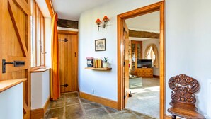 Un pasillo con puertas de madera, una estantería con libros, un espejo y una silla de madera.
