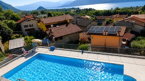 Ein rechteckiger Swimmingpool mit glasklarer, blauer Wasseroberfläche, umgeben von einer gefliesten Liegefläche und einem Metallgeländer.