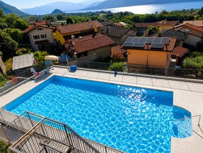 A rectangular swimming pool with a clear blue surface, surrounded by a tiled deck and a metal railing. - Stunning Pool Apartment With Lake View (Brezzo di Bedero)