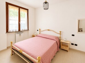 A bedroom with a bed, bedside tables, a window, a radiator, and a hanging light fixture. - Stunning Pool Apartment With Lake View (Brezzo di Bedero)
