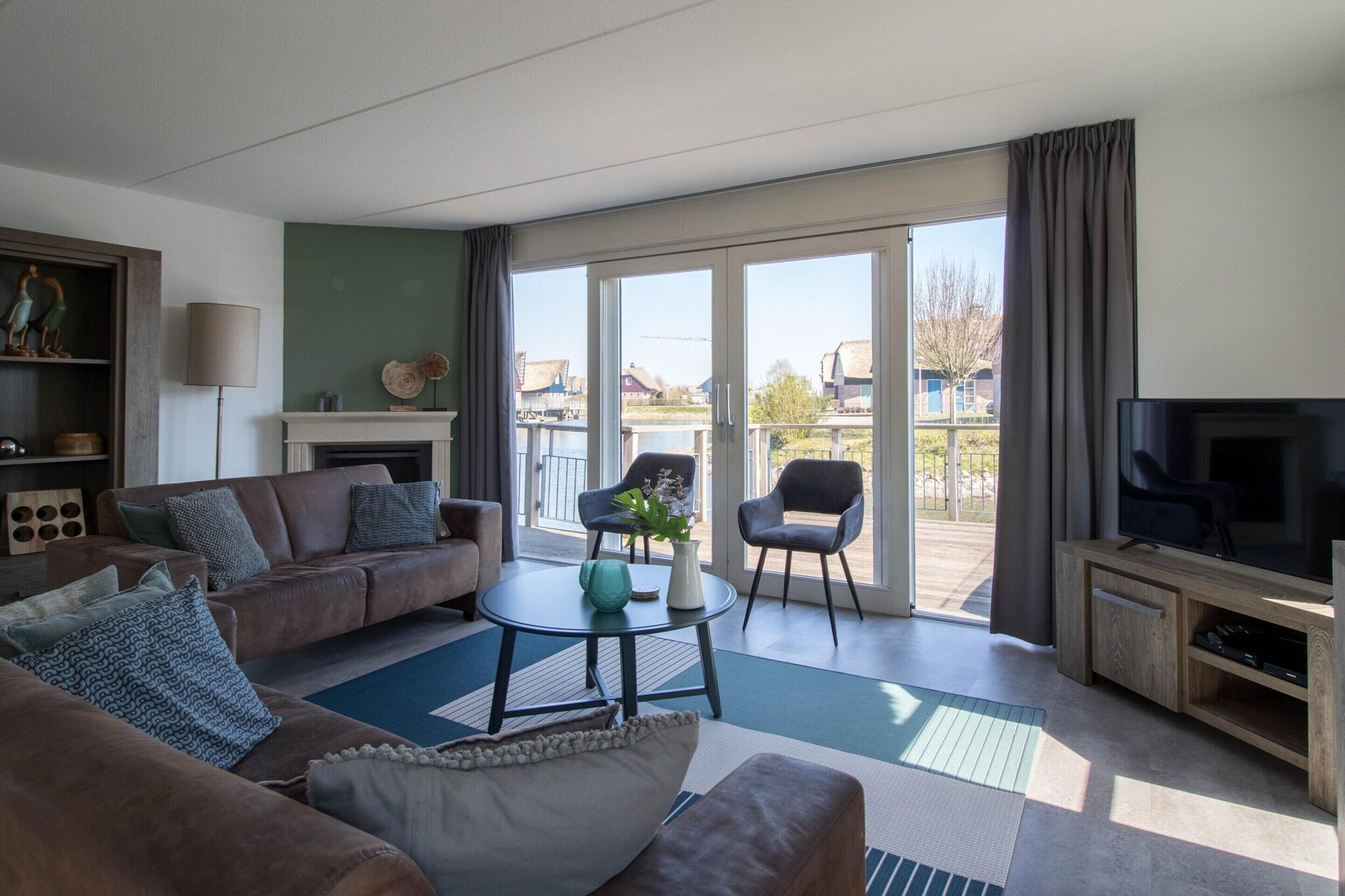 Ein stilvolles Wohnzimmer mit einer Couch, Sesseln, einem Couchtisch und einem Fernseher.