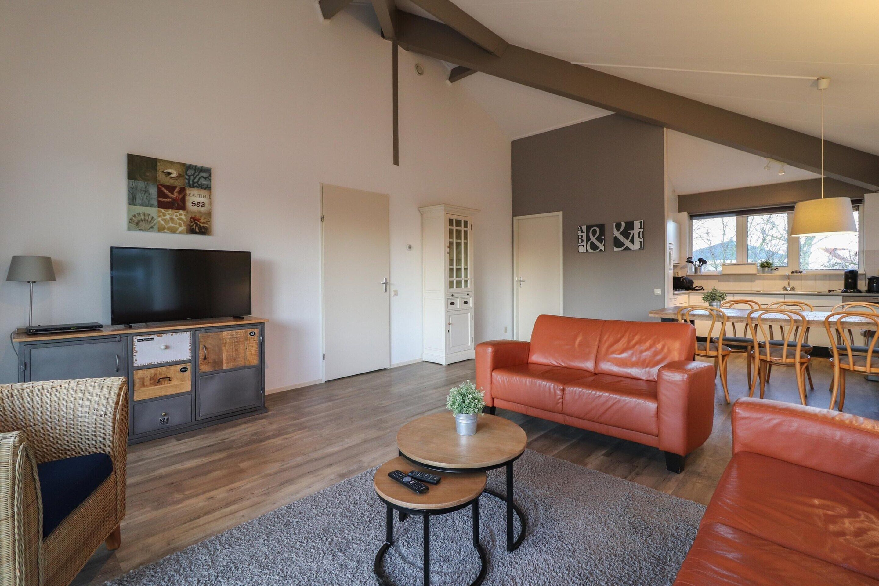A modern living room with a television, sofa, and dining area.