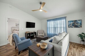 Ein Wohnzimmer mit Sofa, Sessel, Couchtisch und Deckenventilator.
