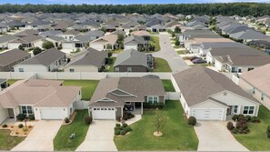A residential area with multiple houses, each with a garage, driveway, and lawn. - Coastal Cottage | Golf Cart & Near Sawgrass (Wildwood)