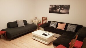 Una sala de estar con dos sofás, una mesa de centro y una mesita con un objeto decorativo.