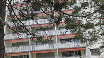 A multi-story building with balconies, surrounded by trees.