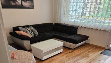 Ein Wohnzimmer mit einem Ecksofa, einem kleinen Tisch und einem gelben Sessel.