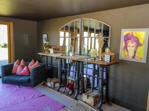 Ein Zimmer mit einer Couch, einem Tisch mit diversen Gegenständen, einem Spiegel und einem Gemälde an der Wand.