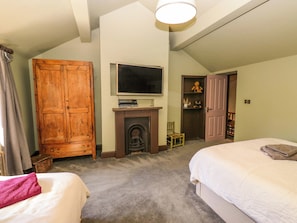 Ein Schlafzimmer mit zwei Betten, einem Holzschrank, einem Fernseher über einem Kamin und einer Tür zu einem Schrank.