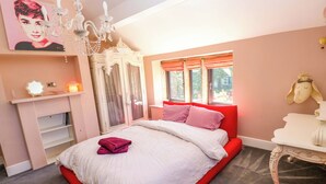 Une chambre à coucher avec un lit, un lustre, une commode et une fenêtre avec des rideaux.