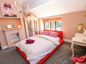Ein Schlafzimmer mit Bett, einer Chandelier, einem Schminktisch und einem Fenster mit Vorhängen.