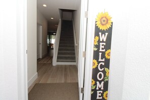 A hallway with a staircase leading to another room, a welcome sign with sunflowers, and a doormat. - Luxury Disney Private Nature trees in every -de (Clermont)