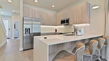 A modern kitchen with a central island, stainless steel appliances, and bar stools.
