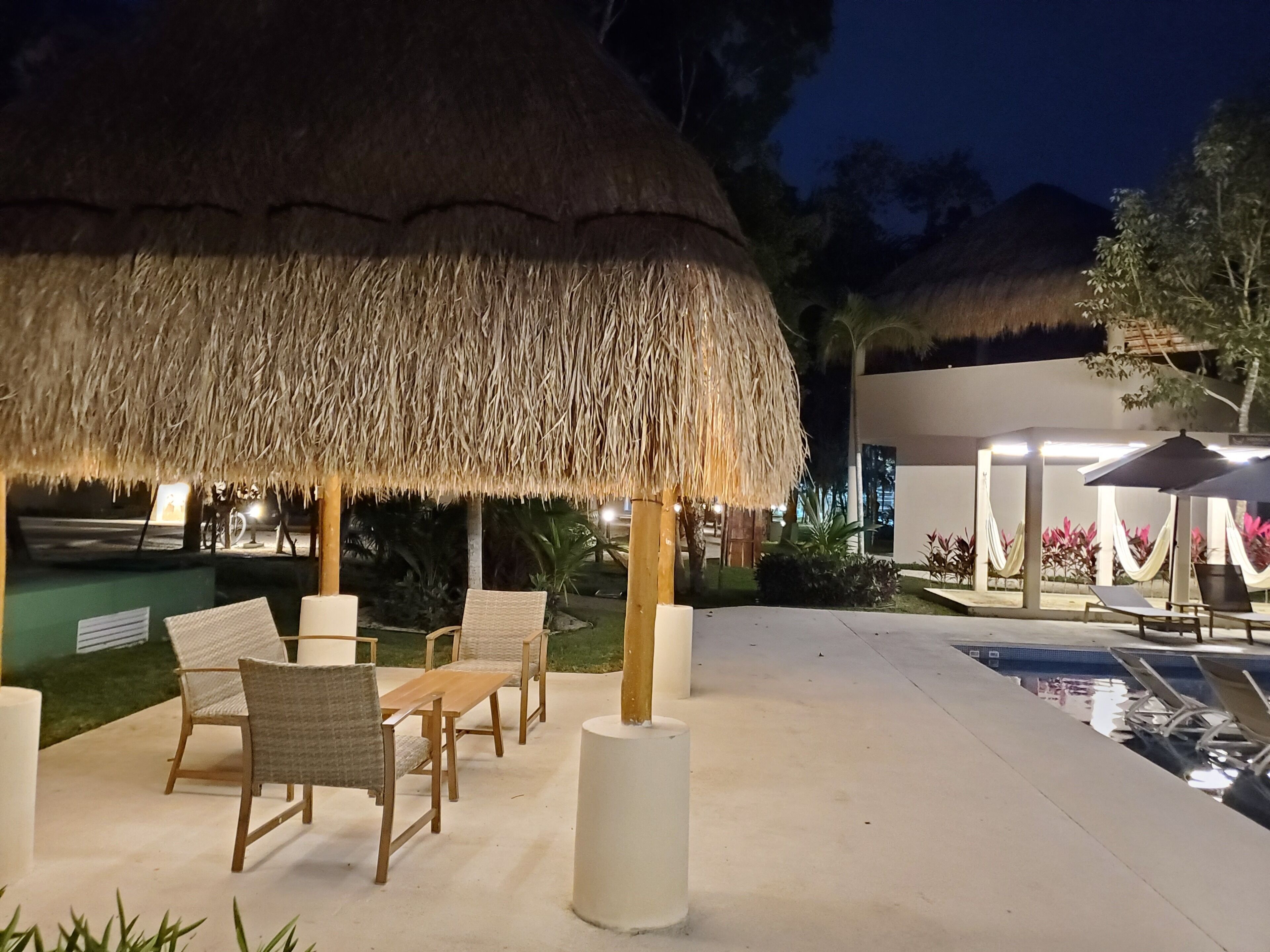 Een zwembadgedeelte met rieten parasols, lounge stoelen en een zwembad.